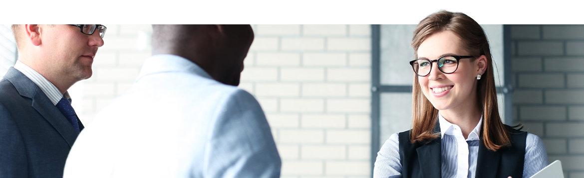 Smiling female lawyer greeting a same-sex couple in a law building.